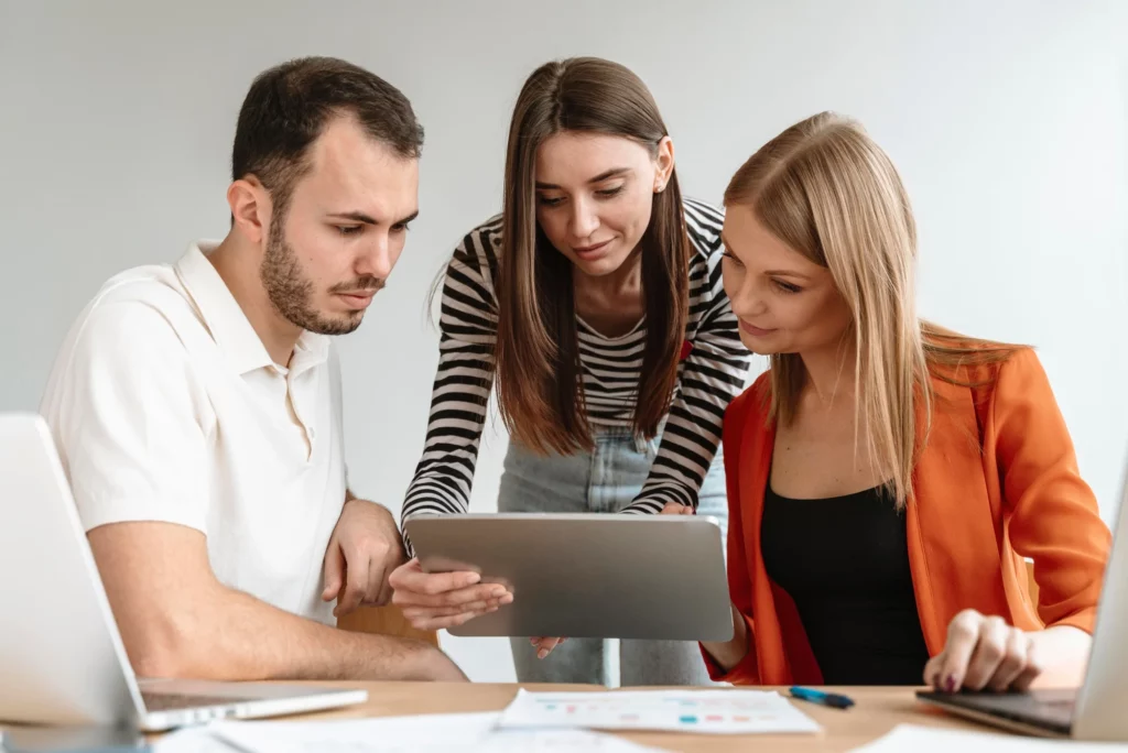 Trois collaborateurs échangeant autour d'une tablette lors d'une réunion de travail