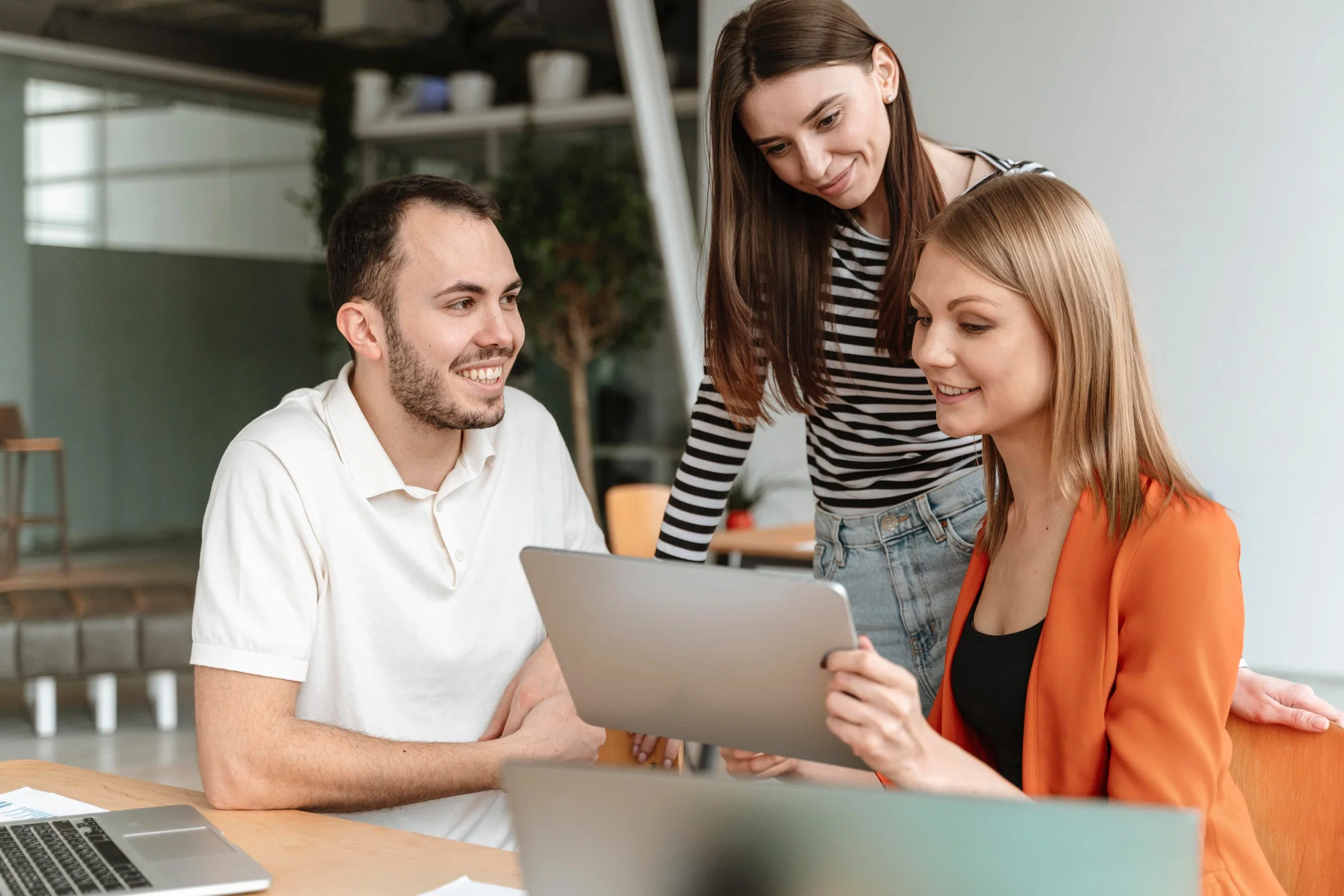 Équipe échangeant autour d'une tablette pour préparer des contenus et des supports de communication